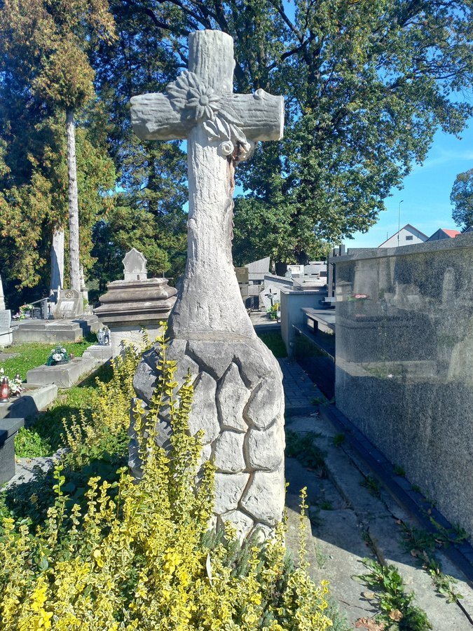 Kamienny nagrobek z krzyżem i zniszczoną tablicą na cmentarzu w Ciężkowicach, widok od frontu